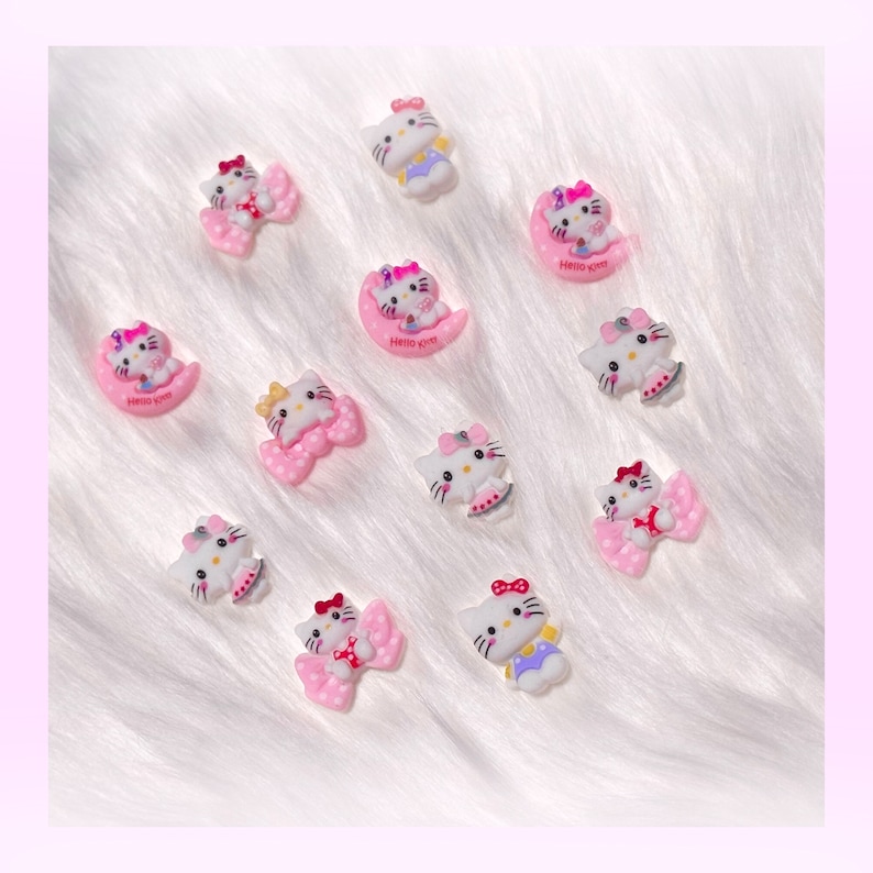 May include: Assortment of Hello Kitty charms featuring Hello Kitty in various poses, including wearing a dress, a bow, and a moon. The charms are made of white plastic with pink, purple, and blue accents.