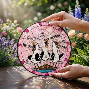 May include: A round, stained-glass art piece featuring three cartoon seagulls with open beaks. The seagulls are standing on a small island with the text "MRS. SMITH!" surrounding the image in a pink and white color scheme.