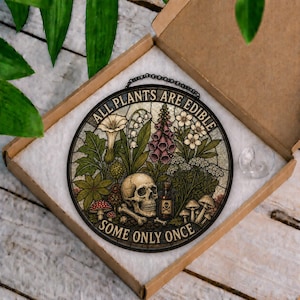 May include: Round stained glass art piece with a botanical and skull design. The artwork features various plants, mushrooms, a skull, and the text "ALL PLANTS ARE EDIBLE SOME ONLY ONCE". It is displayed in a cardboard box.