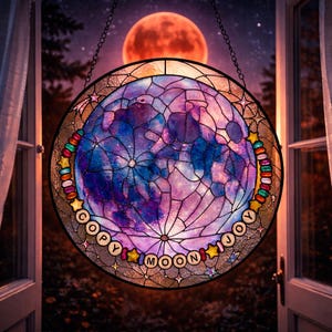 Pu&ograve; includere: Opera d'arte circolare in vetro colorato raffigurante una luna nelle tonalit&agrave; del blu, viola e rosa. Il design include il testo "COPY MOON JOY" ed &egrave; incorniciato da perline colorate e forme di stelle. Una catena &egrave; attaccata per appenderlo.