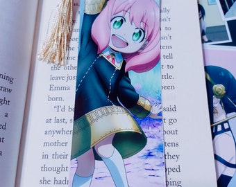 Könnte beinhalten: Ein Lesezeichen mit einem Cartoon-Mädchen mit rosa Haaren, das ein schwarzes und goldenes Outfit trägt, vor einem sternenübersäten Hintergrund. Das Lesezeichen hat einen goldenen Quasten.