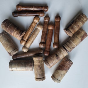 May include: A collection of wooden dowels in various sizes and shades of brown. The dowels are arranged in a circular pattern on a white surface.