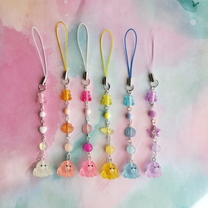 May include: Six colorful phone charms with different charms and beads. Each charm features a clear gummy bear, a clear bead, and a clear seal. The charms are attached to a string with a loop at the top.