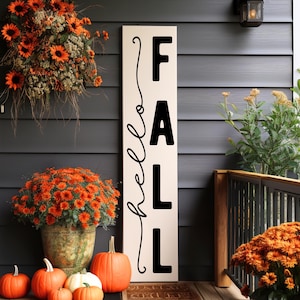 May include: A fall-themed porch display featuring a vertical sign that reads "FALL" with "hello" in cursive. The scene includes orange mums, pumpkins, and a hanging floral arrangement, all set against a dark gray exterior.