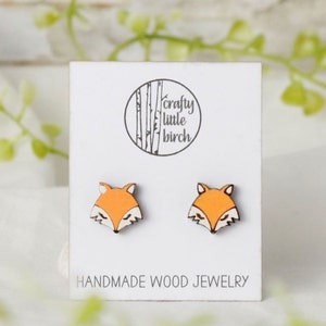 May include: A pair of wooden fox earrings on a white card with the text "crafty little birch" and "HANDMADE WOOD JEWELRY".
