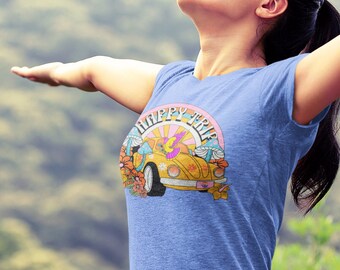 May include: A woman wearing a blue t-shirt with a yellow car and the text "Little hippie soul" printed on it. She is standing with her arms outstretched, looking up at the sky.