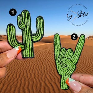 Puede incluir: Dos parches bordados: un cactus verde y una mano verde haciendo un gesto de rock and roll. Ambos parches tienen contornos negros y están colocados sobre un fondo desértico. Los parches están etiquetados 1 y 2.