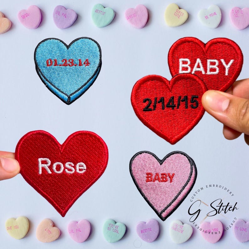 May include: Embroidered heart-shaped patches in red, blue, and pink, with white text including "BABY", "Rose", and dates. Pastel heart candies with phrases like "BESTIE" and "BE MINE" surround the patches.