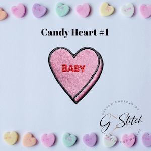 May include: A pink embroidered heart-shaped patch with the word "BABY" in red. The patch has a black border and is labelled "Candy Heart #1". Pastel candy hearts with phrases like "BESTIE" and "BE MINE" surround the patch.