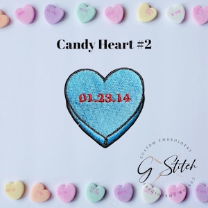May include: A light blue embroidered heart-shaped patch with the date 01.23.14 in red. The patch is surrounded by various pastel-coloured candy hearts with phrases like "BESTIE" and "BE MINE". The text "Candy Heart #2" is above the patch.