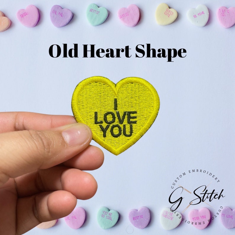 May include: A yellow embroidered heart-shaped patch with the words "I LOVE YOU" in black. The patch is held in a hand, surrounded by pastel-coloured heart-shaped sweets with various phrases. The image is labelled "Old Heart Shape".
