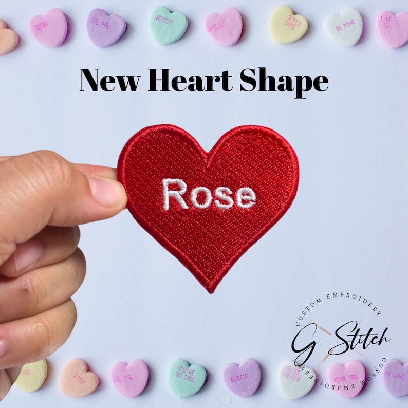 May include: A red heart-shaped embroidered patch with the word "Rose" in white. The image also features the text "New Heart Shape" and several pastel-coloured heart-shaped candies with various phrases.