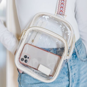 A woman wearing a clear sling bag with a woven strap.