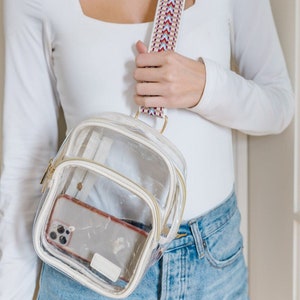 A woman wearing a clear sling bag with a woven strap.