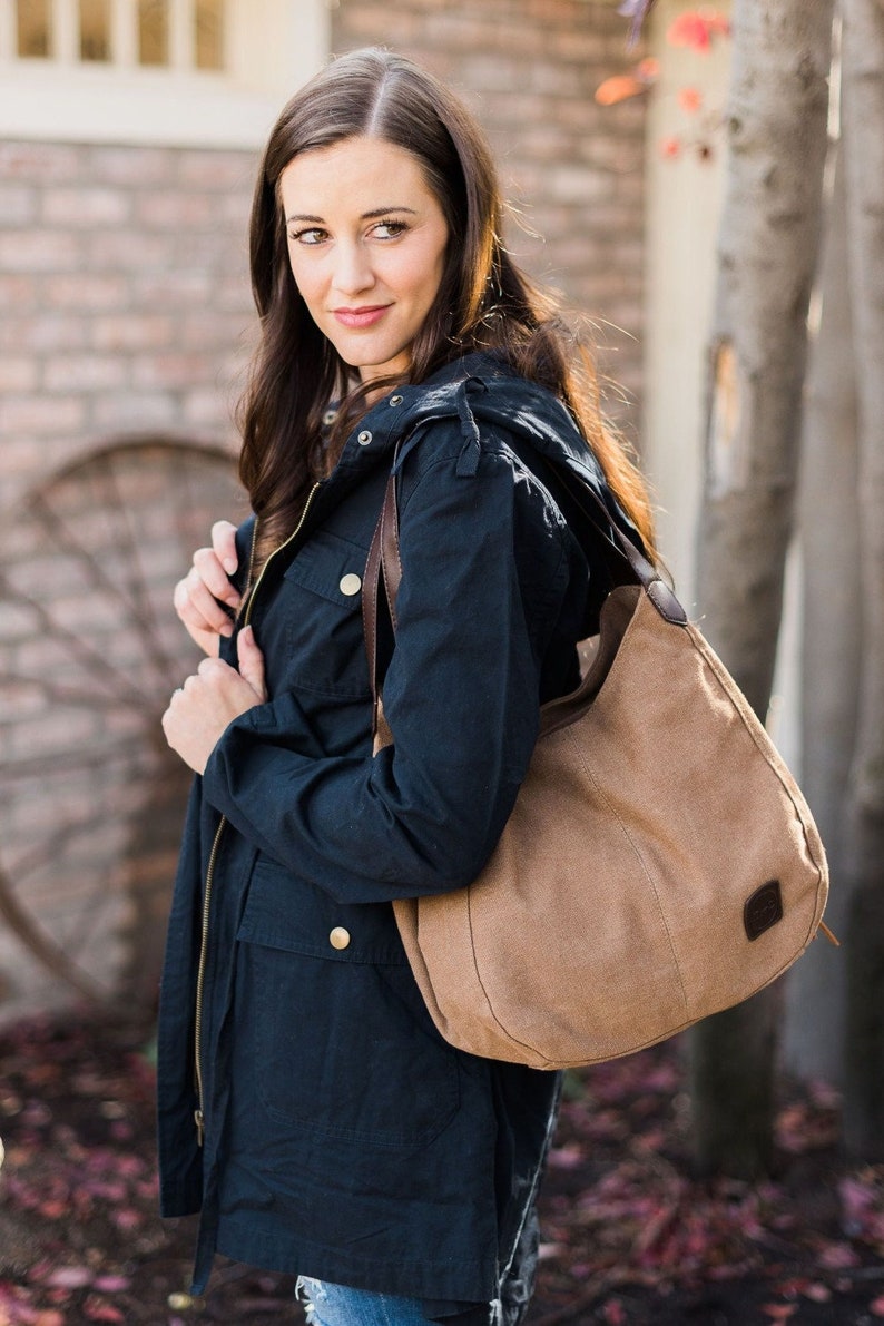 A woman wearing a cargo jacket and a brown hobo bag on her shoulder.