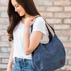 A woman wearing navy canvas hobo bag on her shoulder.