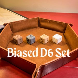May include: A set of six wooden dice with numbers 1 through 6, in a brown leather dice tray. The dice are all different colors, and the tray has a hexagonal shape. The text "Biased D6 Set" is printed on the tray.