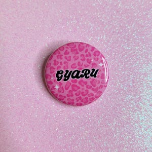 May include: Pink button with a leopard print design and the word "gyaru" in black text.