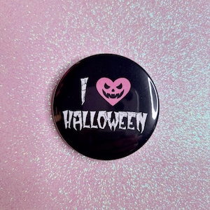 May include: A black button with a white "I love Halloween" text and a pink heart with a jack-o-lantern face.