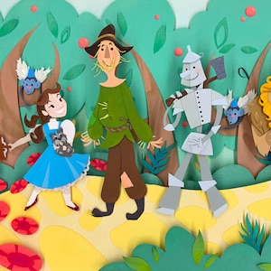 May include: A papercraft illustration of Dorothy, the Scarecrow, the Tin Man, and the Cowardly Lion from the Wizard of Oz. The characters are walking down the yellow brick road, surrounded by green trees and red flowers.
