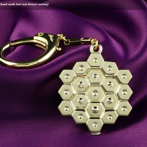 May include: Gold-toned hex nut key chain with a honeycomb design. The chain is attached to a metal ring.