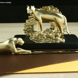 May include: Gold cheetah letter holder with a cheetah sculpture and a letter opener. The cheetah letter holder is made of titanium gold and is hand-made using the lost-wax bronze casting method.