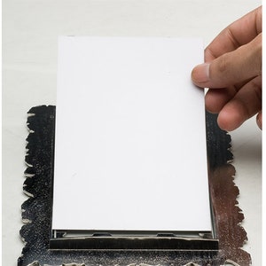 May include: A silver picture frame with an ornate design. A blank white card is placed in the frame.