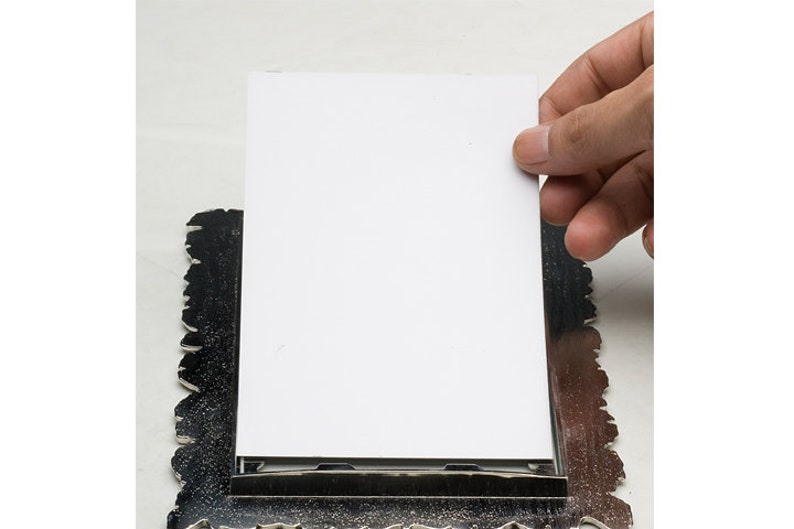 May include: A silver picture frame with an ornate design. A blank white card is placed in the frame.