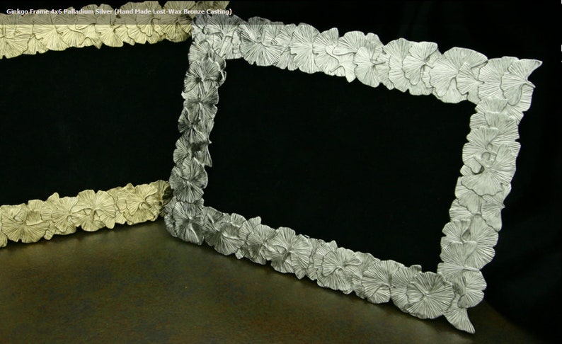 May include: Two silver picture frames with a ginkgo leaf design. The frame on the left is a lighter shade of silver and the frame on the right is a darker shade of silver.