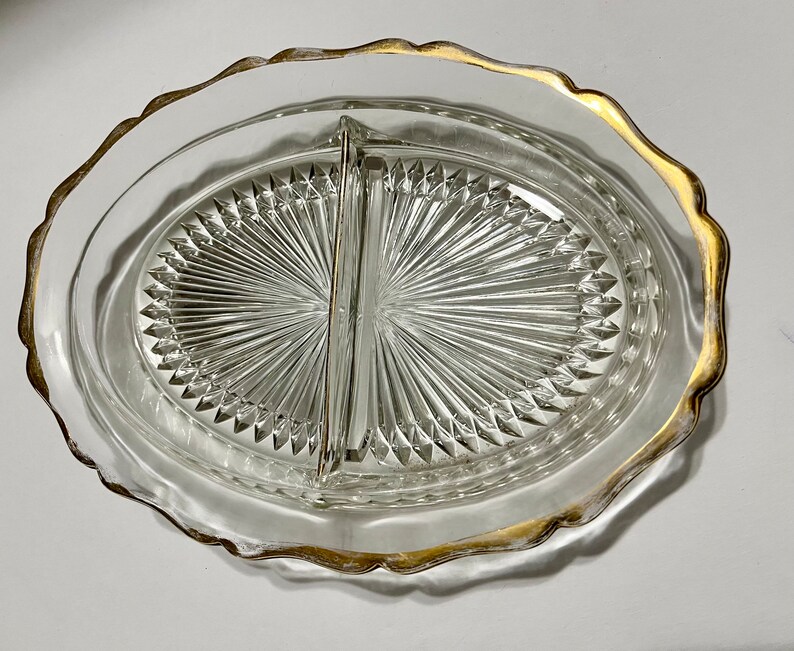 May include: A clear glass divided serving dish with a gold rim. The dish has a diamond pattern and is divided into two sections.