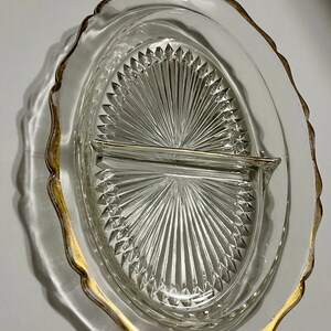 May include: A clear glass divided serving dish with a gold rim. The dish has a scalloped edge and a diamond pattern.