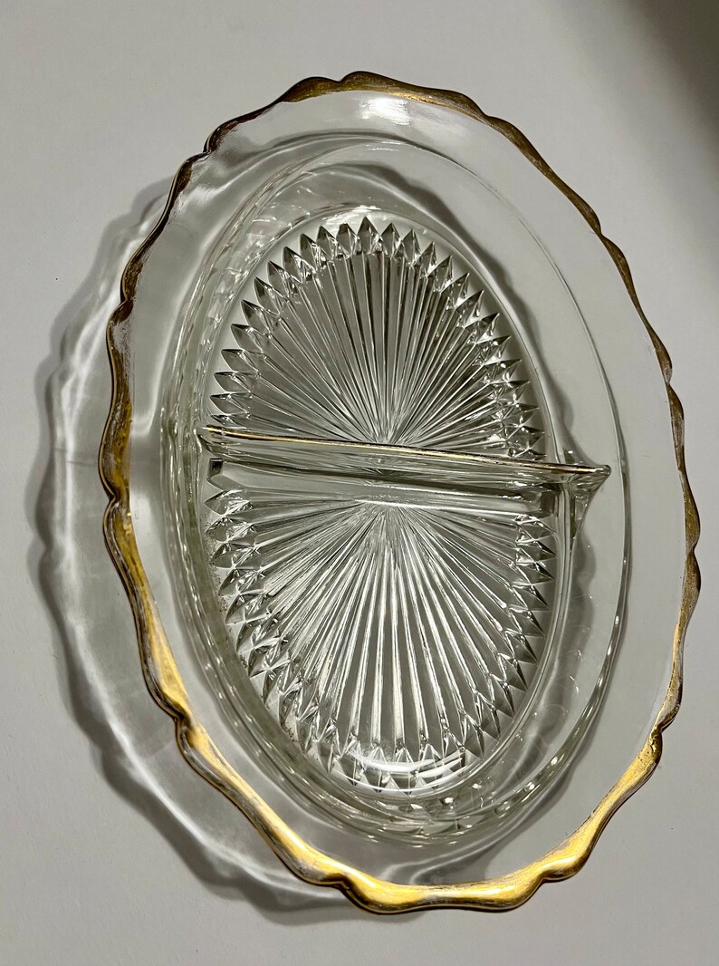 May include: A clear glass divided serving dish with a gold rim. The dish has a scalloped edge and a diamond pattern.