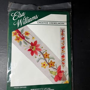 May include: An Elsa Williams Creative Crewelwork kit in a clear plastic bag. The package features a floral design printed on 7.5 inches by 48 inches linen, including crewel wools, a needle, and directions. The graphic shows red and yellow flowers.