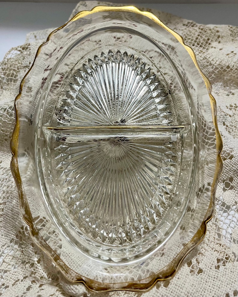 May include: A clear glass divided serving dish with a gold rim. The dish has a diamond pattern and is divided into two sections.