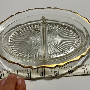 May include: A clear glass divided serving dish with a gold rim. The dish is 6 inches in diameter and has a scalloped edge.