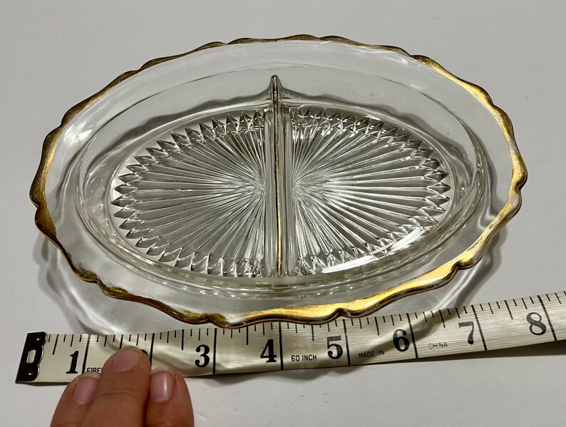 May include: A clear glass divided serving dish with a gold rim. The dish is 6 inches in diameter and has a scalloped edge.