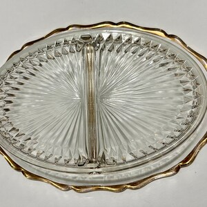May include: A clear glass divided serving dish with a gold rim. The dish has a diamond pattern and is divided into two sections.