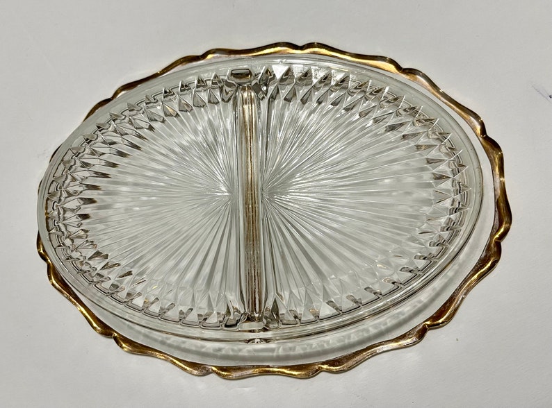May include: A clear glass divided serving dish with a gold rim. The dish has a diamond pattern and is divided into two sections.