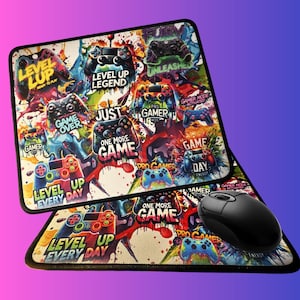 May include: A gaming mouse pad and matching wrist rest featuring a colorful design with game controllers and phrases like "Level Up" and "One More Game." The black mouse sits on the pad, enhancing the gaming theme.