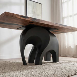 May include: A modern dining table with a dark wood top and a unique black elephant-shaped base. The table's top is rectangular, and the base provides sturdy support. The table is approximately 244 cm long.