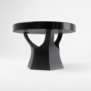 May include: A modern, black round table with a unique base design. The tabletop is a dark color, and the base has a geometric shape with curved supports. The table is approximately 30 inches in diameter.