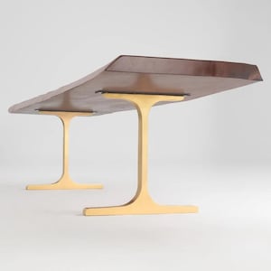 May include: A wooden coffee table with a live edge top and two gold metal T-shaped legs.