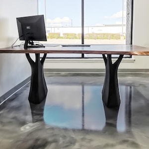 K&ouml;nnte beinhalten: Ein gro&szlig;er Holzschreibtisch mit einer dunkelbraunen Platte und schwarzen baumf&ouml;rmigen Beinen. Ein Computermonitor und eine Tastatur stehen auf dem Schreibtisch. Der Schreibtisch ist etwa 183 cm lang.