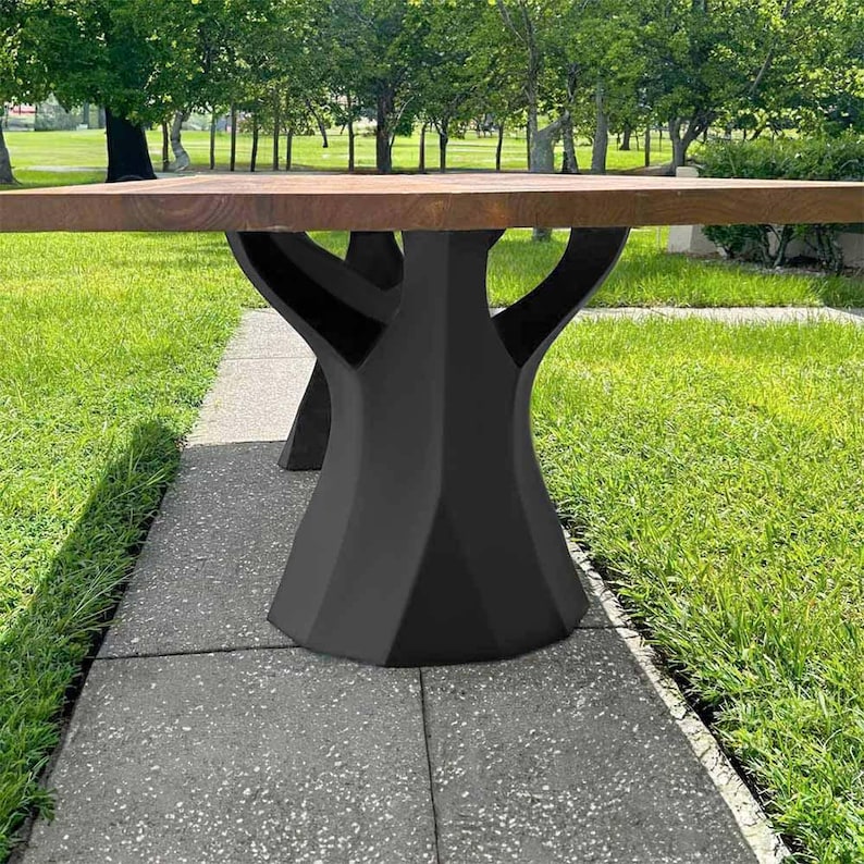 K&ouml;nnte beinhalten: Ein moderner Holztisch mit einer dunkelbraunen Tischplatte und einem schwarzen geometrischen Gestell. Der Tisch steht auf einem Betonweg mit gr&uuml;nem Gras im Hintergrund. Die Abmessungen des Tisches sind nicht sichtbar.