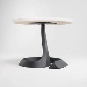 May include: A round white table with a black, curved, and abstract base.