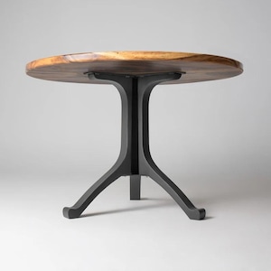 May include: A round wooden table top with a black metal base. The base has three legs that extend out from a central column.