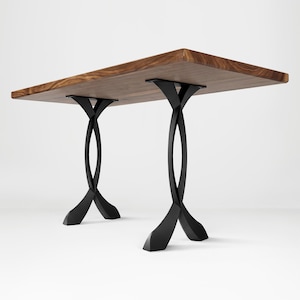 May include: A rectangular wooden table with a natural wood grain finish. The table is supported by two black, curved metal legs. The table's dimensions are approximately 72 inches long and 36 inches wide.