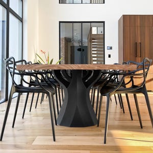 K&ouml;nnte beinhalten: Ein modernes Esszimmer-Set mit einem gro&szlig;en Holztisch mit einem einzigartigen schwarzen Fu&szlig; und mehreren schwarzen Kunststoffst&uuml;hlen. Die Tischplatte ist rechteckig und die St&uuml;hle haben ein unverwechselbares Design mit offenem R&uuml;cken. Der Raum hat gro&szlig;e Fenster und Holzb&ouml;den.