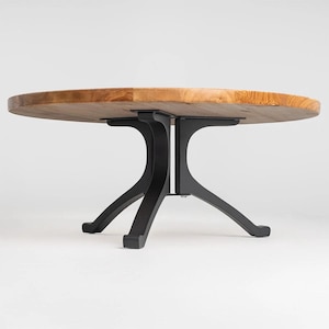 May include: A round wooden coffee table with a black metal base. The table has a natural wood finish and the base has a sleek, modern design.