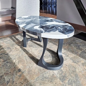 May include: An oval coffee table with a white, gray, and black marbled top. The table has a dark gray base with curved legs. The table is approximately 48 inches long and 24 inches wide.